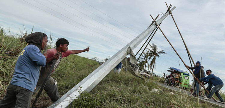 Hier stellen ein paar Männer mit vereinten Kräften einen Strommast auf