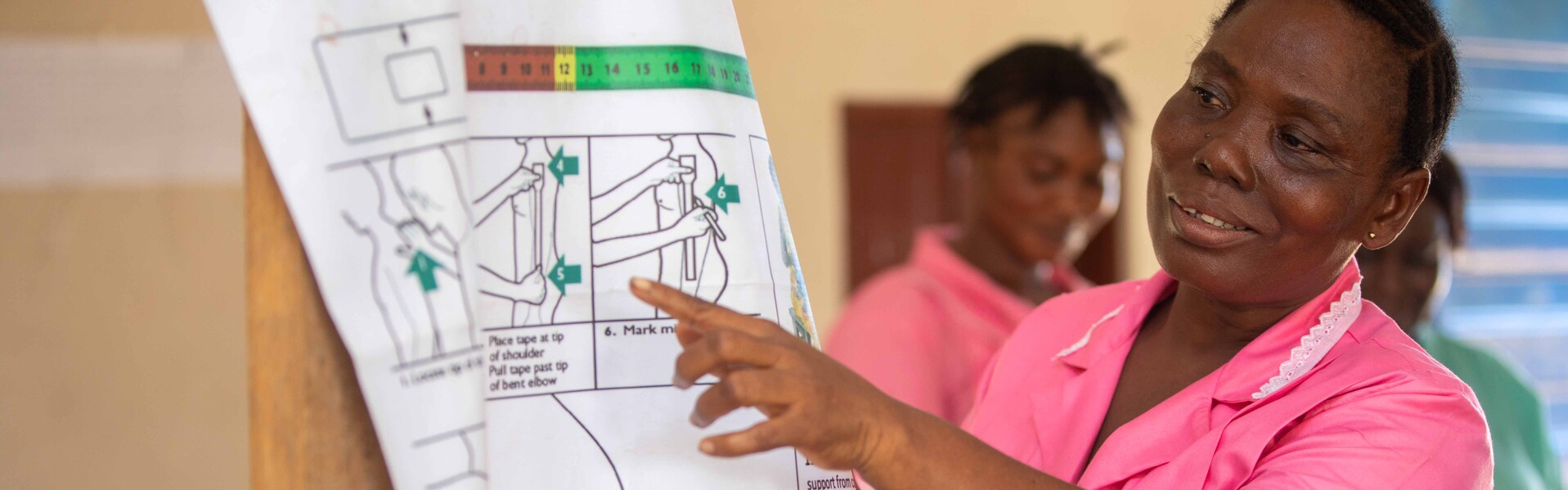 Eine Frau erklärt in Sierra Leone ein Plakat