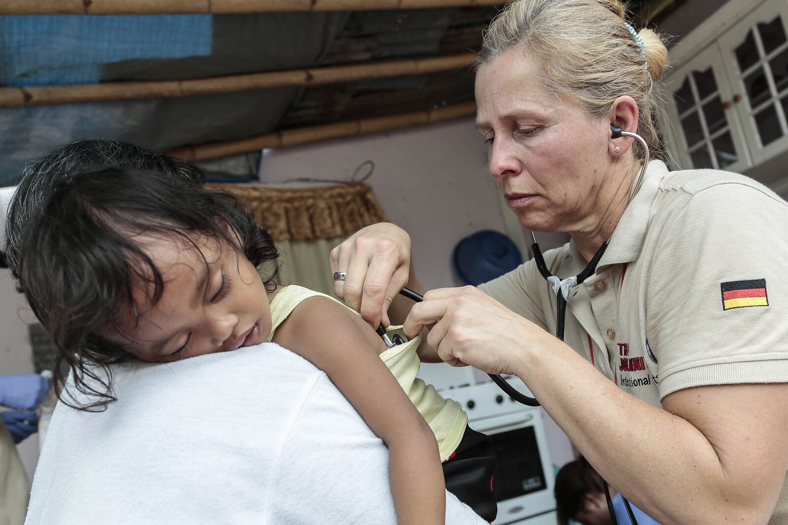 Nach dem Taifun Haiyan auf den Philippinen untersucht eine Ärztin der Johanniter ein kleines Mädchen, das im Arm ihrer Mutter liegt