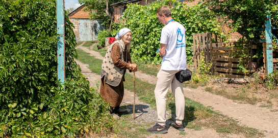 Ein Helfer von Handicap International spricht mit einer älteren Frau