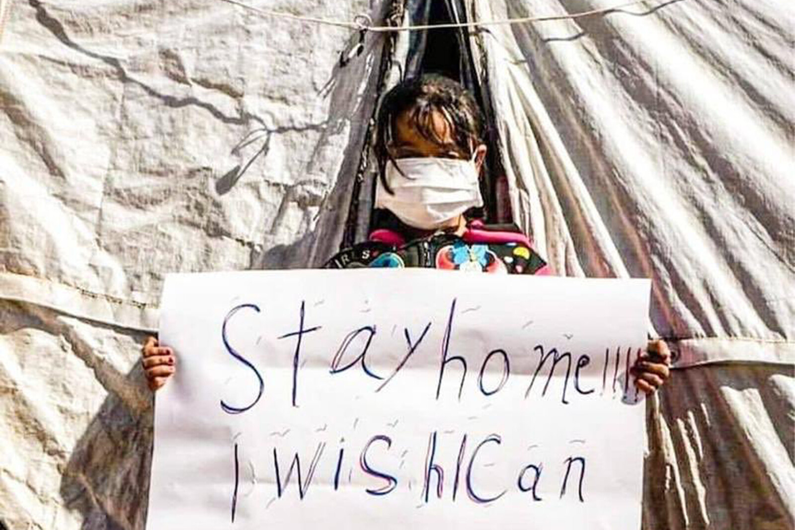 "Stay home, I wish I could" – Kind in Syrien mit einem Schild 