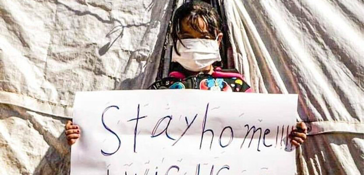 "Stay home, I wish I could" – Kind in Syrien mit einem Schild "Stay home, I wish I could" – Kind in Syrien mit einem Schild