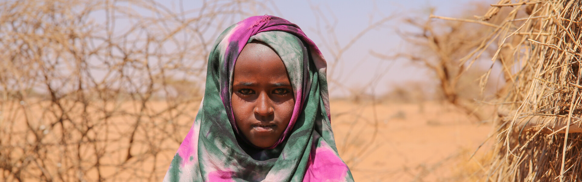 Ein Mädchen steht in Somalia inmitten einer vertrockneten Landschaft