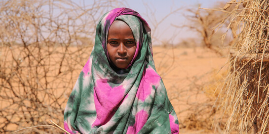 Ein Mädchen steht in Somalia inmitten einer vertrockneten Landschaft