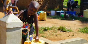 Ein Kind an einer Wasserausgabestelle in Uganda