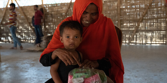 Eine Frau in Bangladesch hält ihre kleine Tochter und eine Tüte mit Seife in der Hand