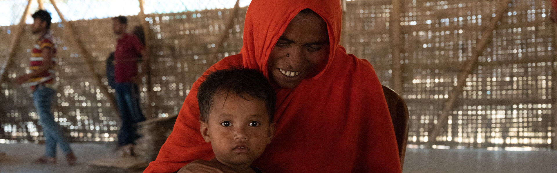 Eine Frau in Bangladesch hält ihre kleine Tochter und eine Tüte mit Seife in der Hand