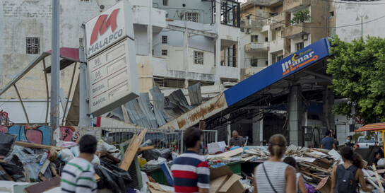 Eine Gruppe von Menschen läuft an einem Trümmerhaufen vorbei, verursacht von den schweren Explosionen in Beirut, Copyright: Help – Hilfe zur Selbsthilfe/Sophia Maier  