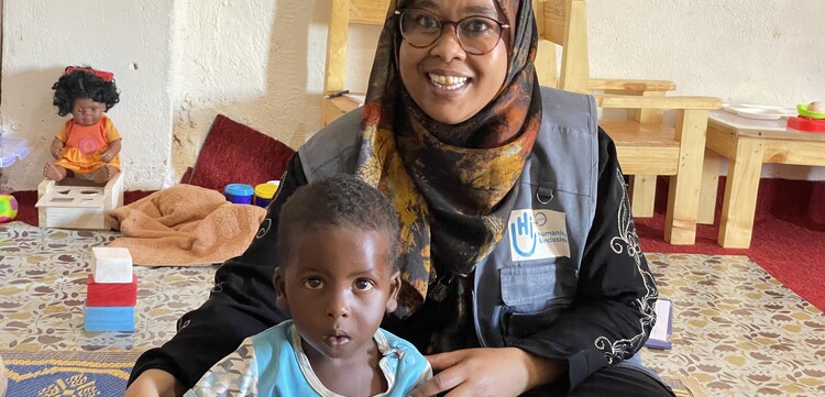Eine Helferin von Handicap International mit dem 17 Monate alten Abdelirah Mohamed Hassan Eine Helferin von Handicap International mit dem 17 Monate alten Abdelirah Mohamed Hassan