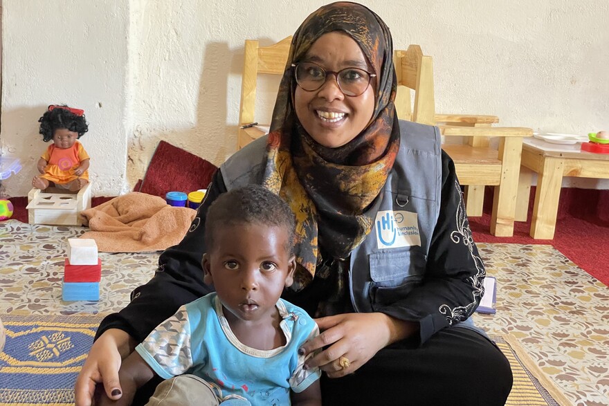 Eine Helferin von Handicap International mit dem 17 Monate alten Abdelirah Mohamed Hassan Eine Helferin von Handicap International mit dem 17 Monate alten Abdelirah Mohamed Hassan