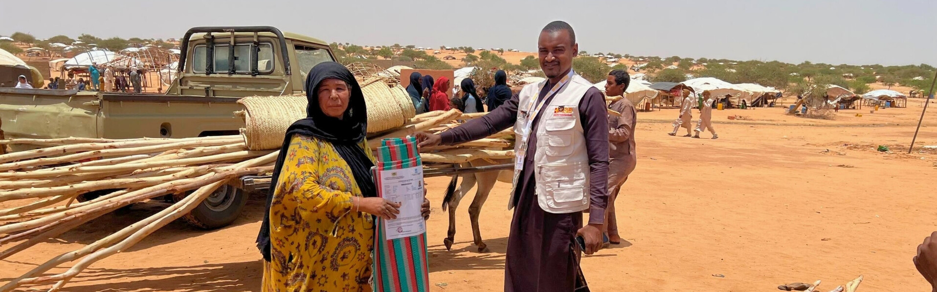 Helfer verteilen an Vertriebene aus dem Niger Baumaterial 