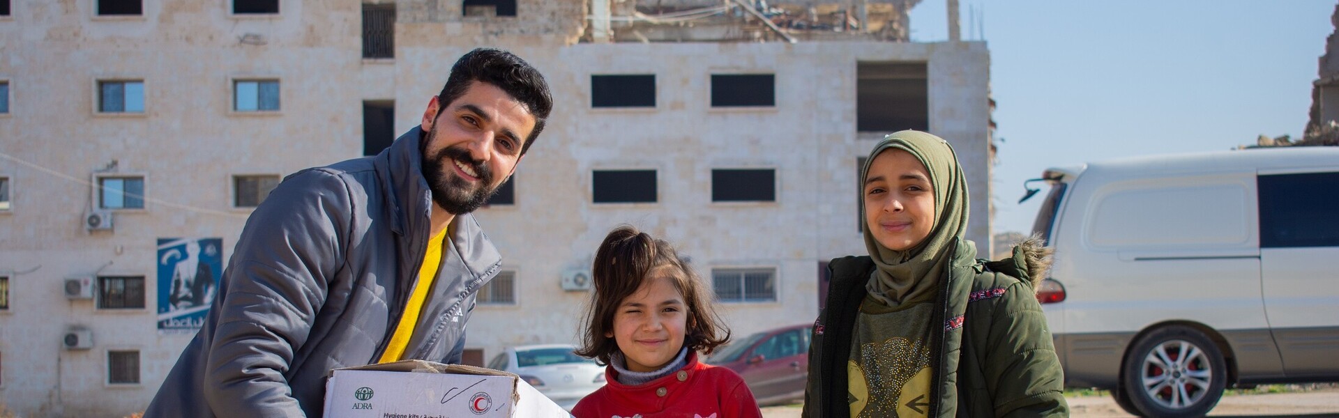 Ein Helfer von der Organisation ADRA übergibt Kindern aus dem Erdbebengebiet in Syrien Hygieneartikel