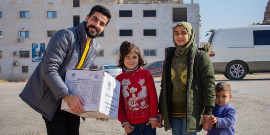 Ein Helfer von der Organisation ADRA übergibt Kindern aus dem Erdbebengebiet in Syrien Hygieneartikel