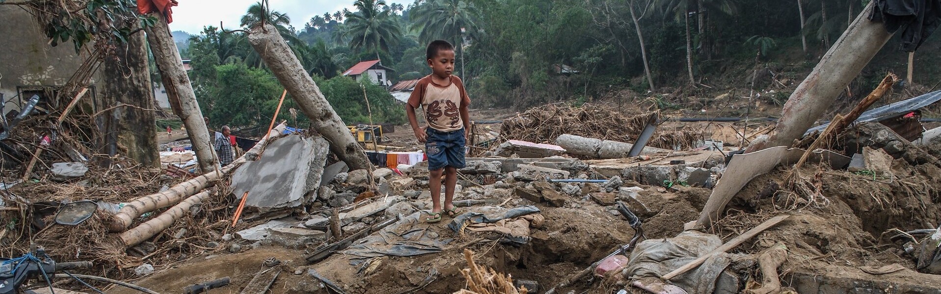 Ein Junge zwischen Trümmern, die die Taifune in Südostasien hinterlassen haben Ein Junge zwischen Trümmern, die die Taifune in Südostasien hinterlassen haben