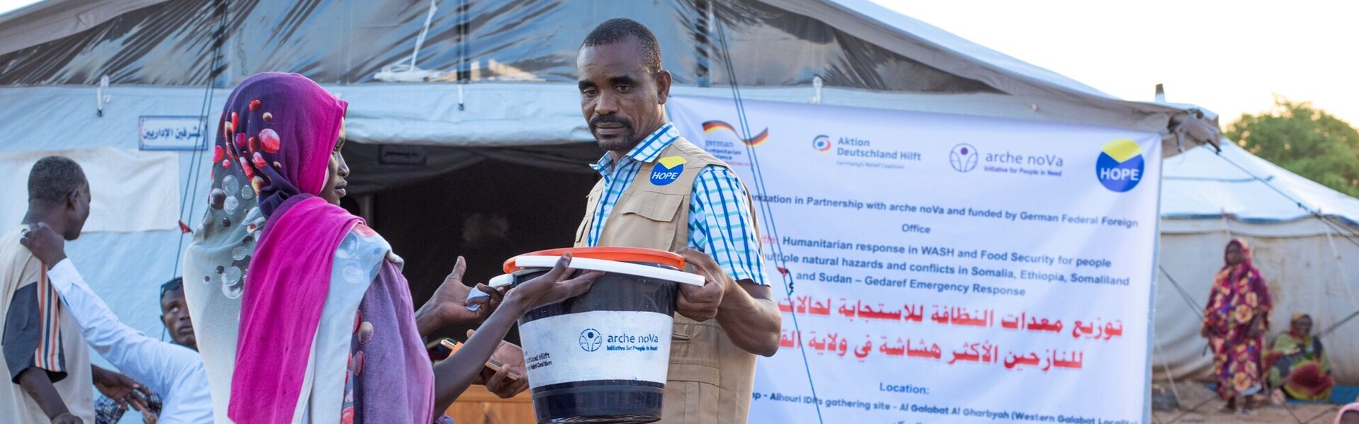 Ein Helfer im Sudan überreicht einer Frau ein Hygiene-Kit
