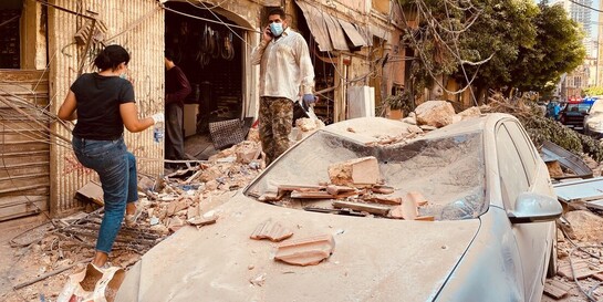 Menschen vor von der Explosion in Beirut zerstörten Häusern