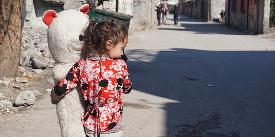 Ein Mädchen läuft mit einem großen Teddybären durch die Straßen in Syrien