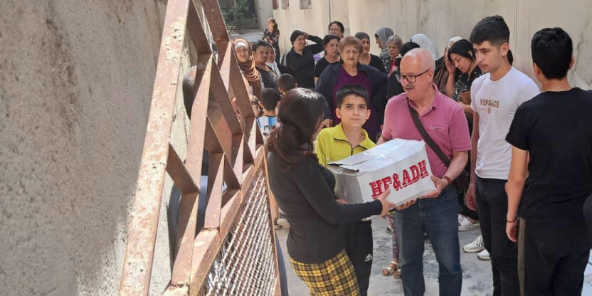 Der Helfer Dr. Ali Al-Zakami übergibt einer Frau in Syrien ein Lebensmittelpaket Der Helfer Dr. Ali Al-Zakami übergibt einer Frau in Syrien ein Lebensmittelpaket