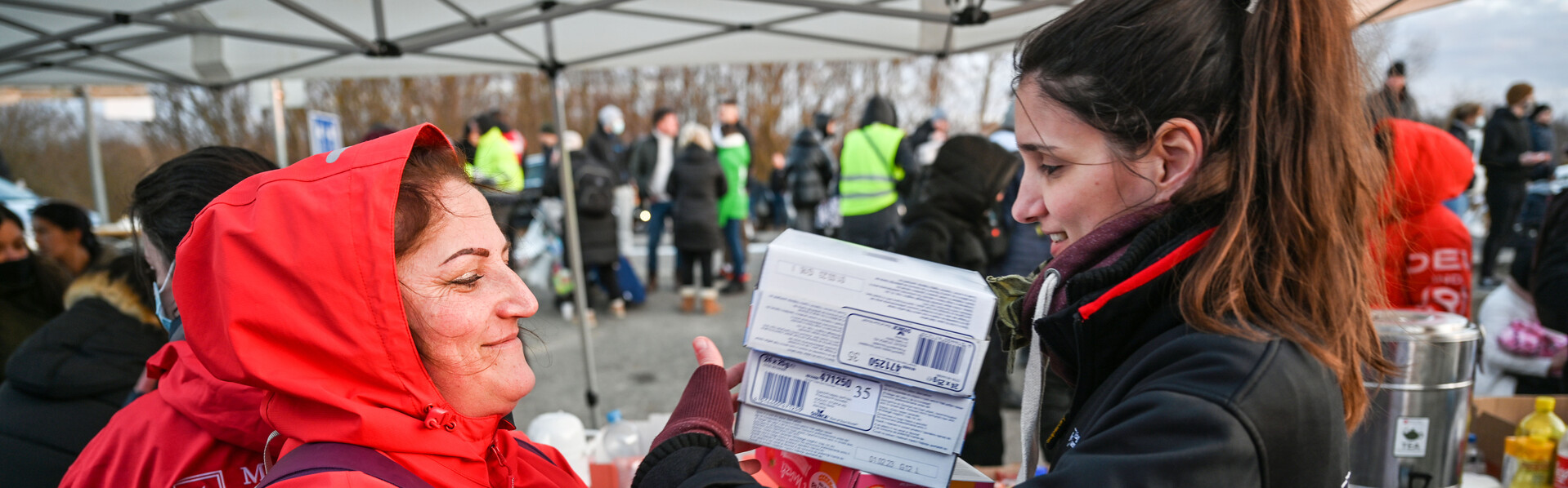 Eine Helferin der Malteser übergibt Hilfsgüter an eine Frau aus der Ukraine