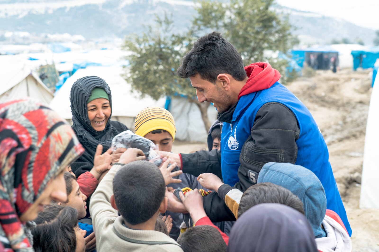 Ein Helfer mit Kindern in einem Flüchtlingscamp