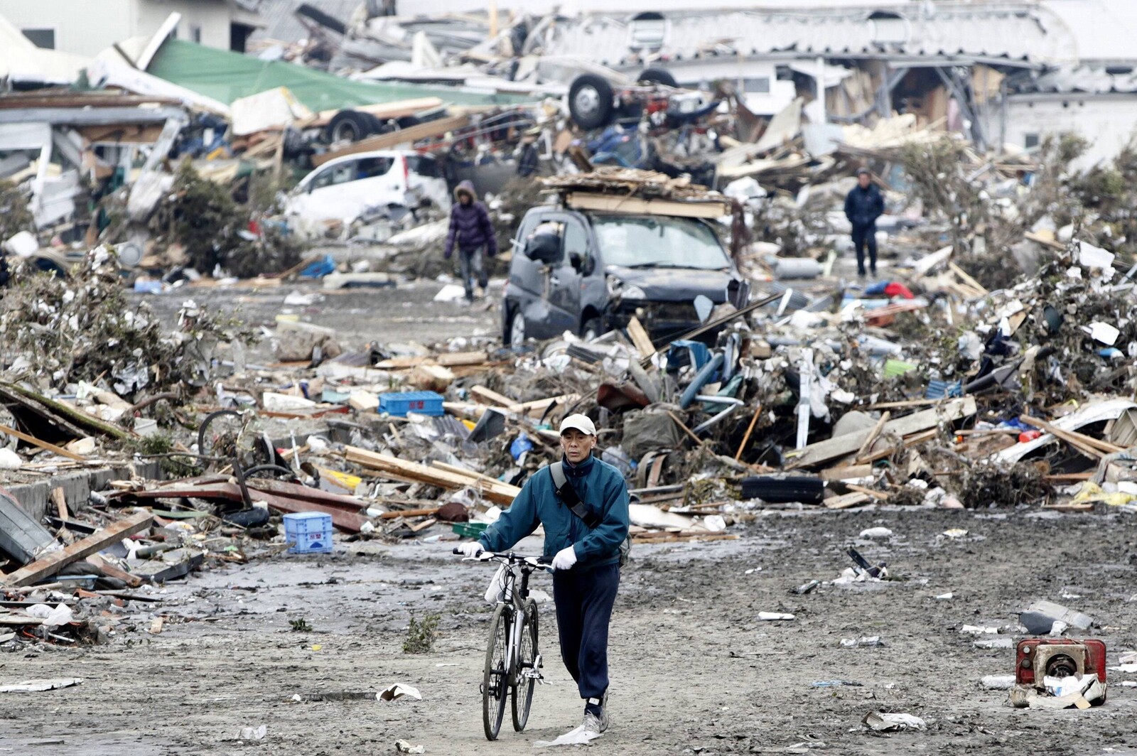 Nach der Katastrophe in Japan 2011 schiebt ein Mann sein Fahrrad durch die Trümmer