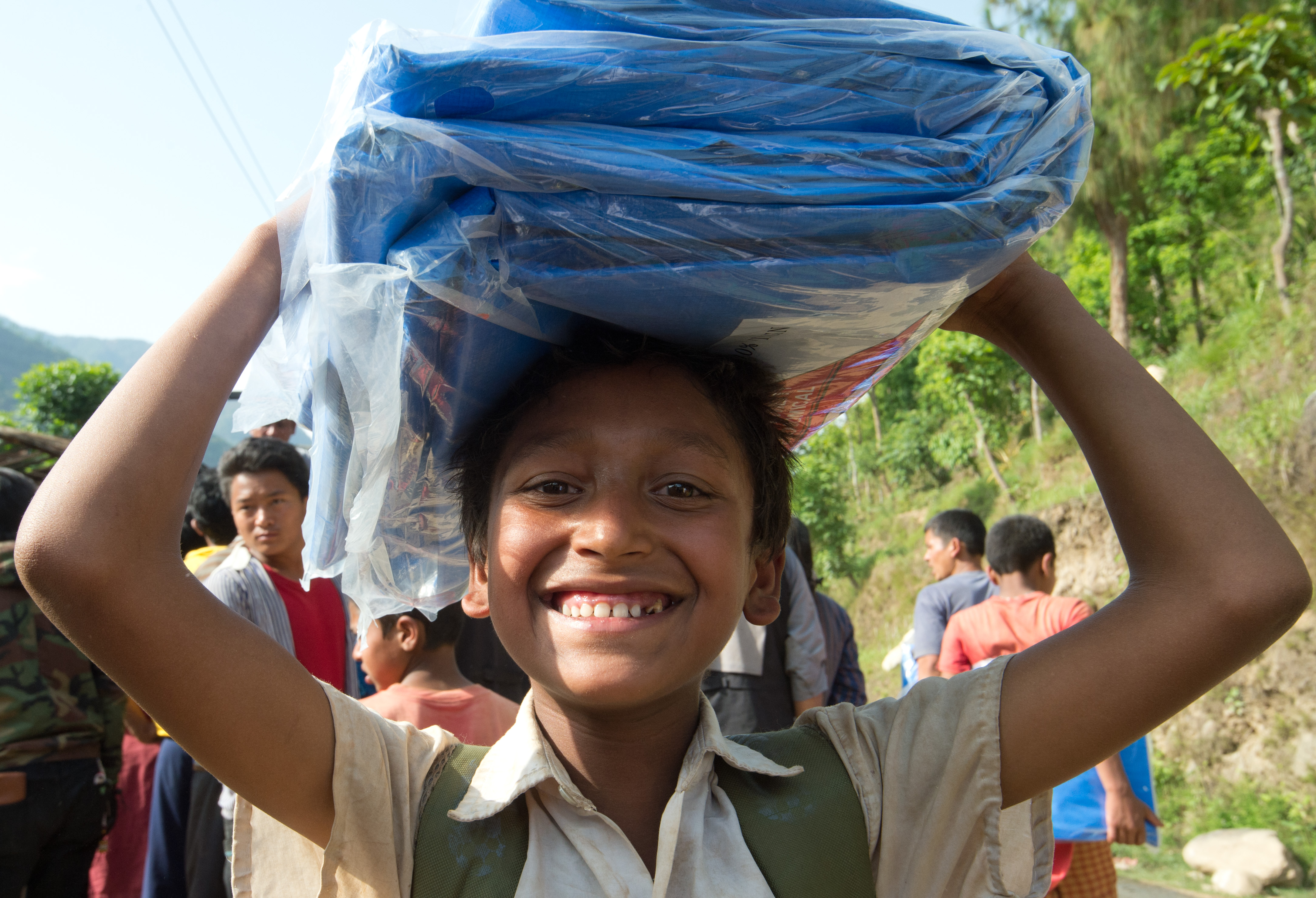 Erdbeben Nepal - Ein Junge erhält Decken und Zeltplanen.