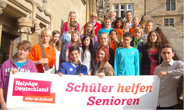 Eine Schulklasse steht mit einem Banner für das Projekt "Schüler helfen Senioren" von HelpAge auf einer Treppe Eine Schulklasse steht mit einem Banner für das Projekt "Schüler helfen Senioren" von HelpAge auf einer Treppe