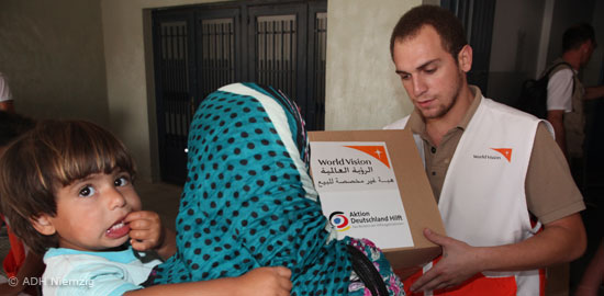Helfer von World Vision übergibt einer Frau ein Nothilfepaket
