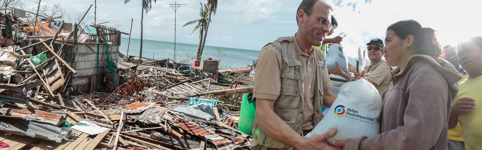 Ein Helfer übergibt einen Sack an einen Betroffenen eines Taifuns auf den Philippinen